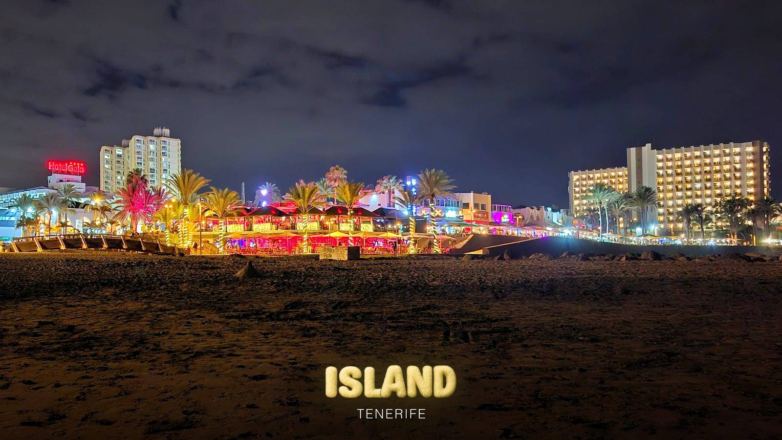 Playa de las Américas seafront at night, Tenerife, with the lights of the bars and hotels and the Party Island Tenerife logo