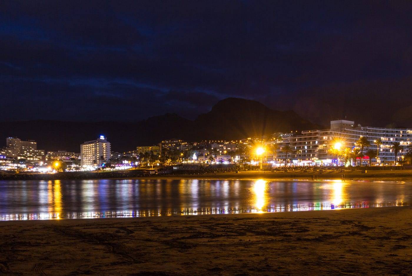 The Costa Adeje seafront at night, with the lights of the promenade reflected in the water